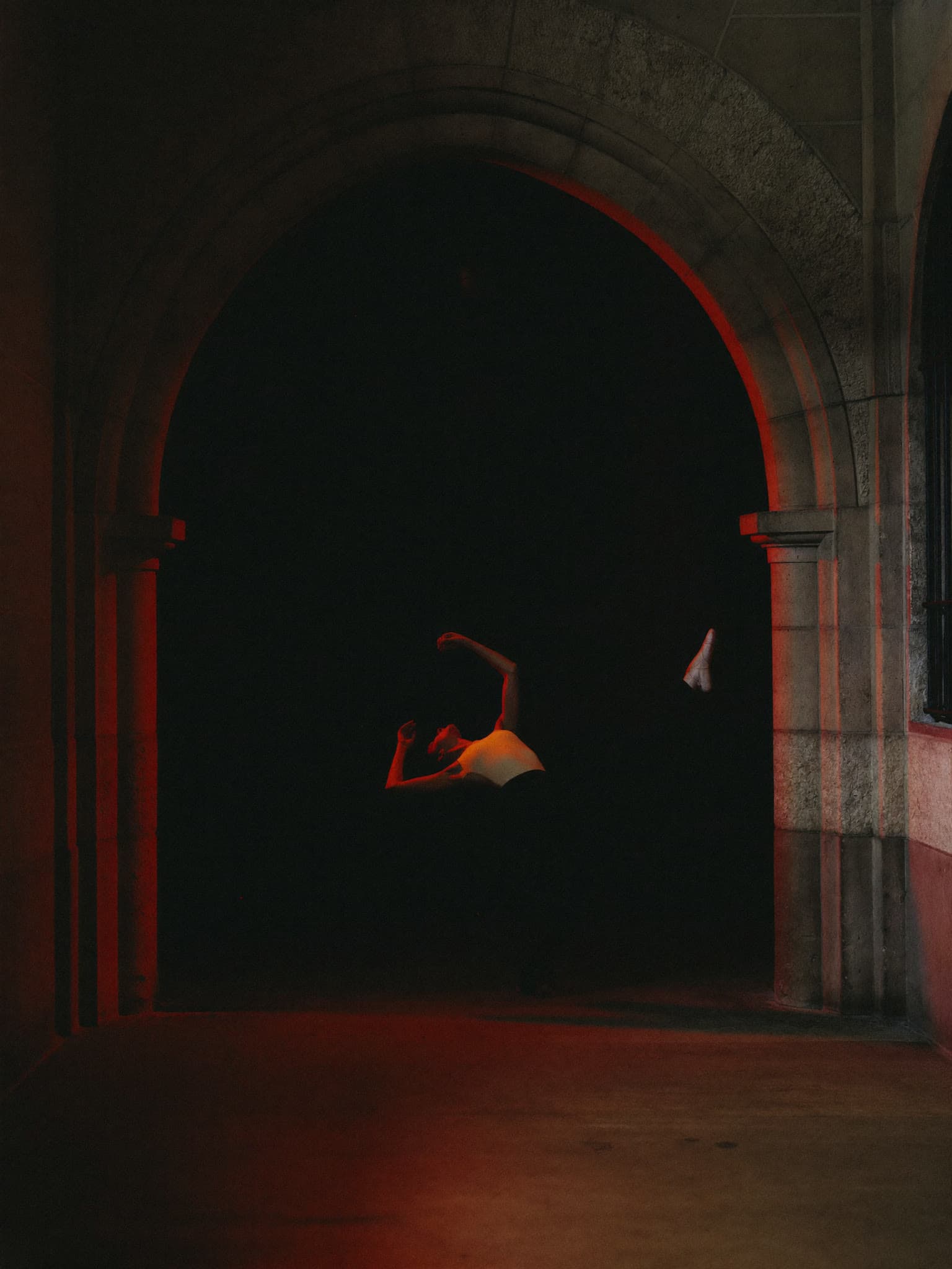 A dancer moving through red light inside the chapel arch at The Black-E